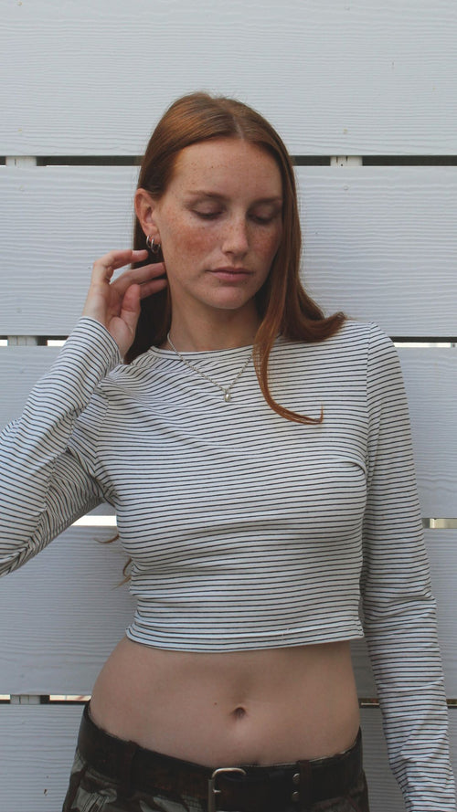 Model in off-white striped long sleeve cotton-spandex crop top, showing midriff.