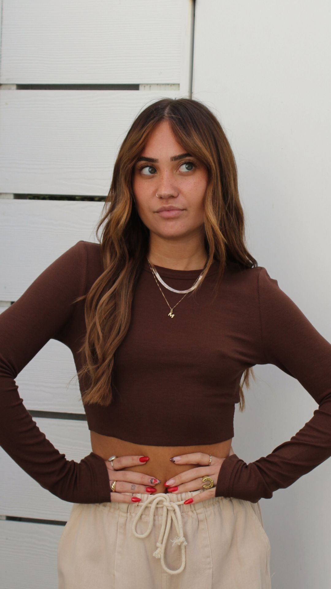 Model in a soft long sleeve ribbed brown cropped top, paired with light-colored drawstring pants.