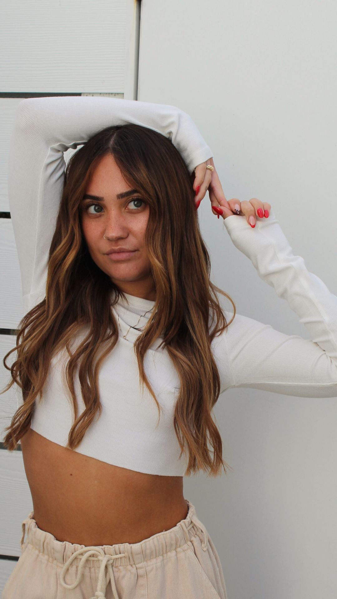 Model in a soft white ribbed long sleeve cropped top, showing the fitted style.
