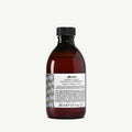 Davines Alchemic Shampoo Tobacco, a dark amber bottle with a black cap and white label.