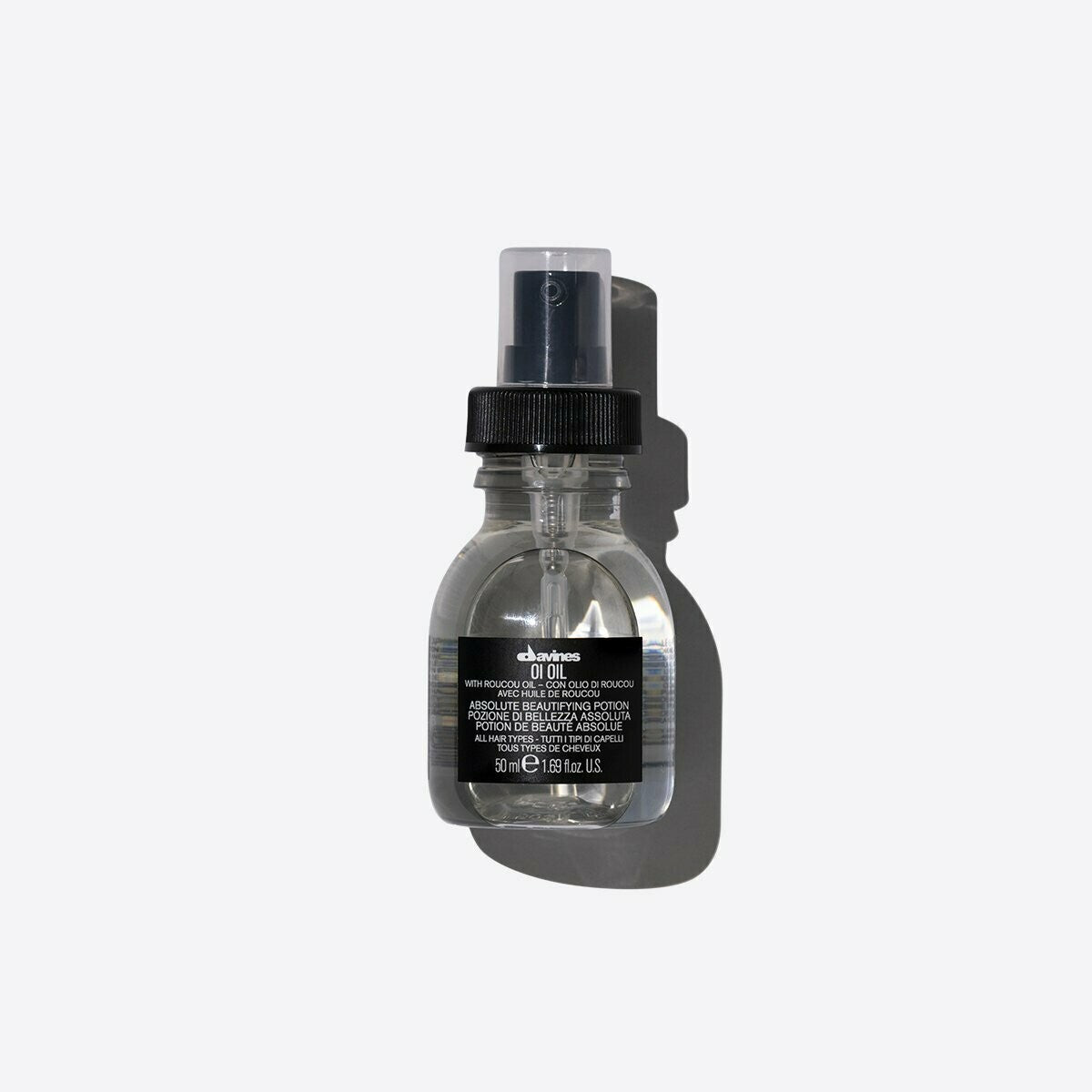 Davines OI Oil 50ml clear bottle with black pump and cap, casting a shadow on a white background.