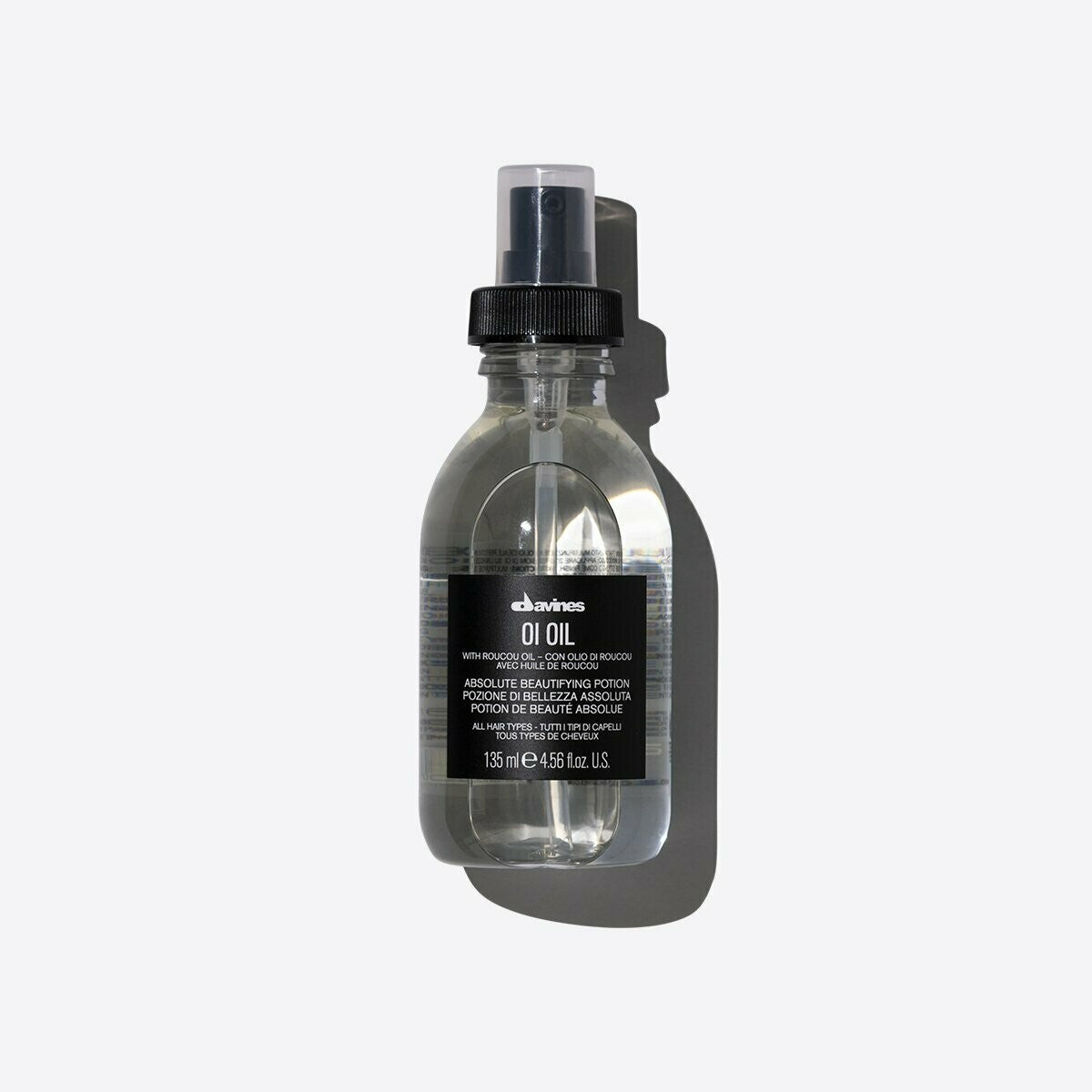 Clear Davines OI Oil 135ml spray bottle with a black label and cap, casting a shadow.