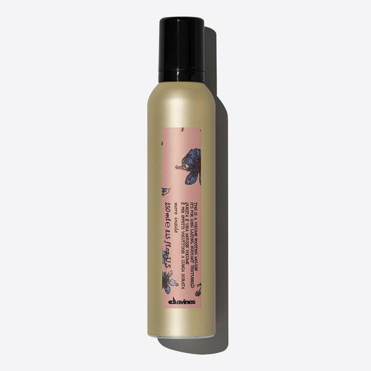 Davines Volume Boosting Mousse in a gold aerosol can with a black cap and pink floral label.