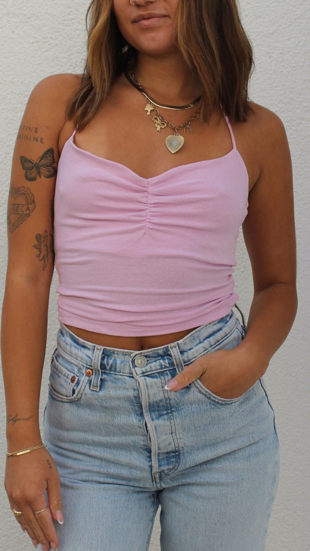Pink cotton-spandex ruched halter top worn by a model in light wash jeans.