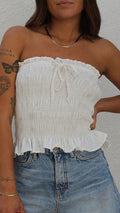 White smocked tube top in viscose-linen blend with ruffled hem and front tie detail.