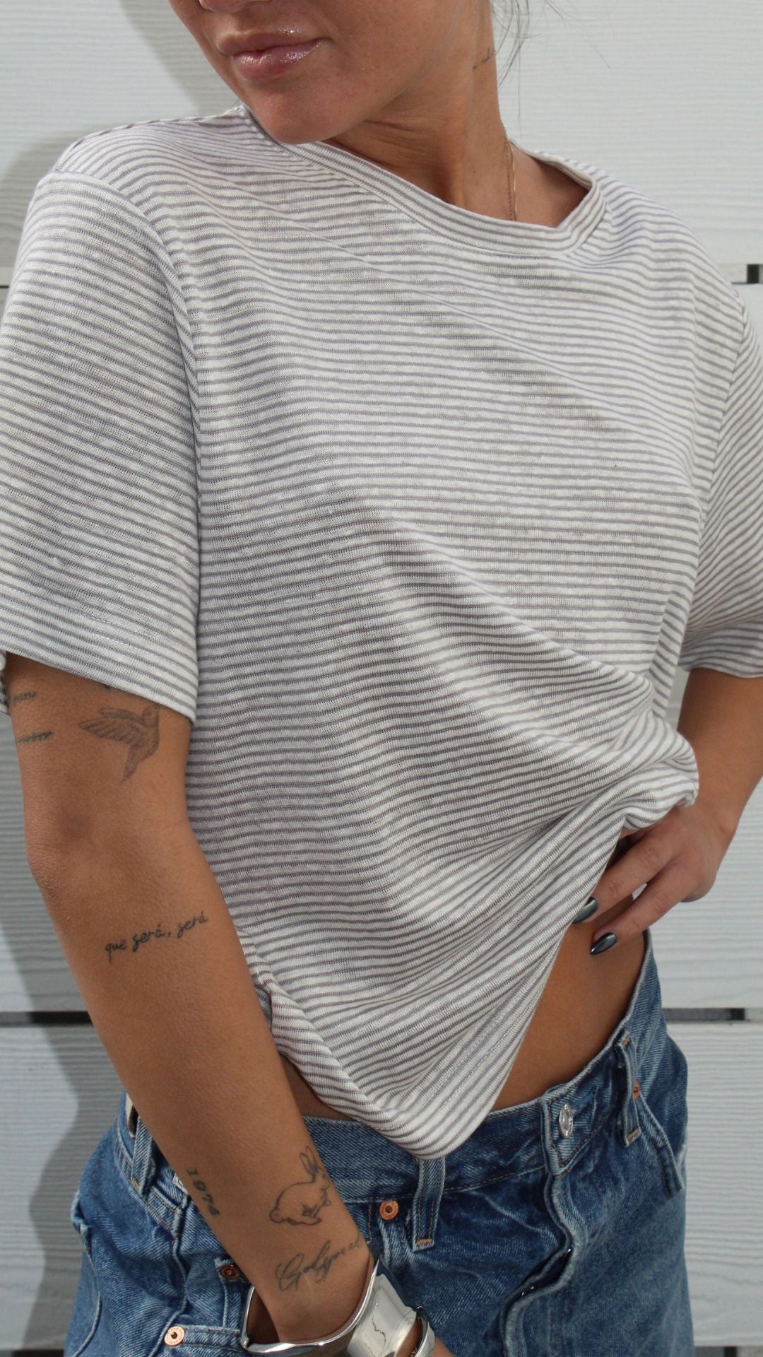 Woman wearing a white and grey striped short sleeve linen-rayon tee with blue jeans.