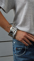 High Tide Cuff: Thick, wavy silver bracelet on a wrist with a striped shirt and jeans.