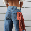 Brown silk bandana with red cherry print tucked into the back pocket of blue jeans.