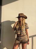 Woman in a brown crochet knit striped top and matching shorts with a cowboy hat.