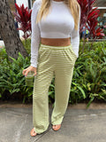 Woman in green and white striped Kiwi Set Pants with elastic waistband, holding a drink.
