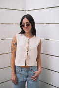 Model in a cream knitted Lasso Top, a tied-front cardigan made of 60% cotton, 40% polyester.