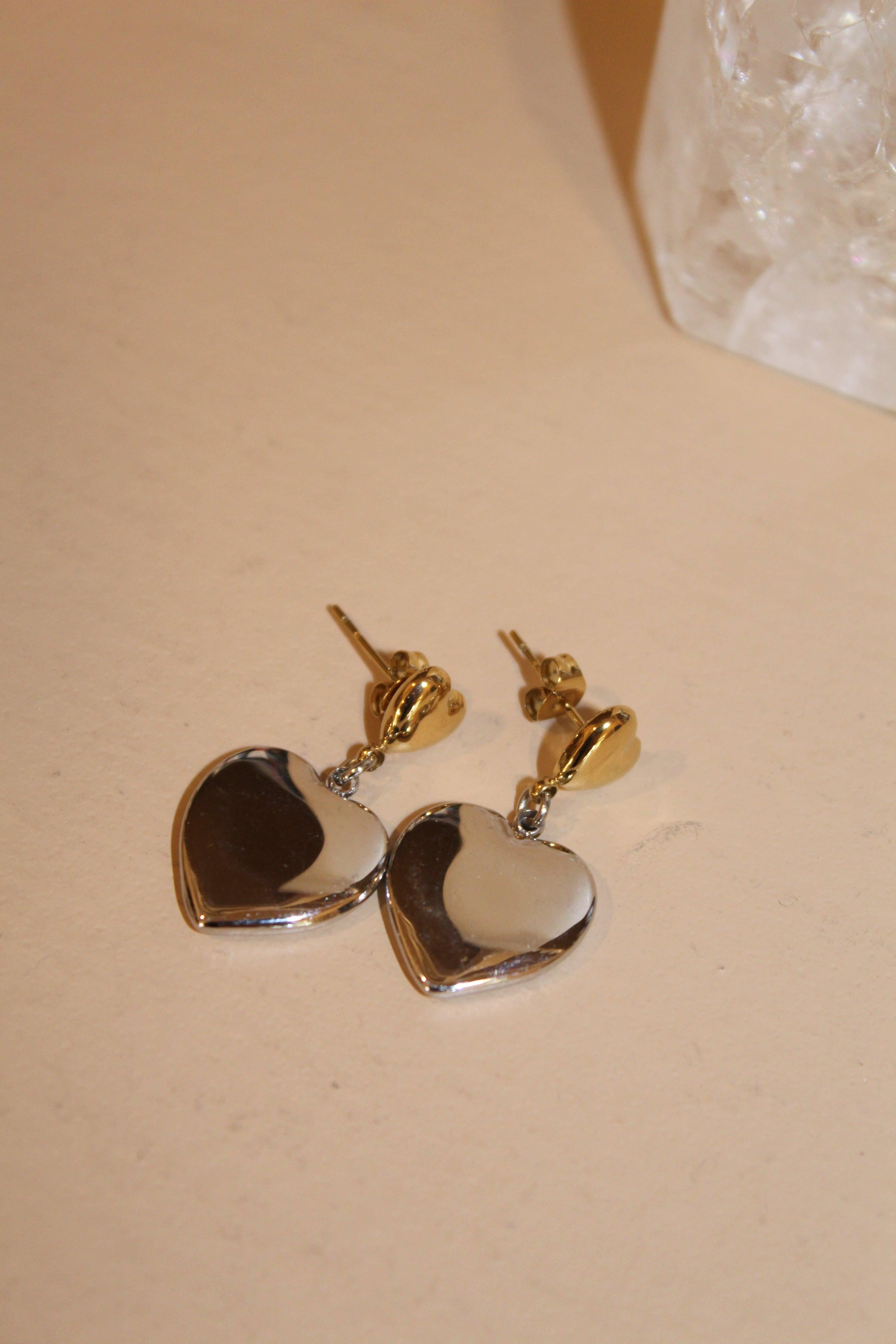 Silver and gold heart-shaped drop earrings with gold studs.
