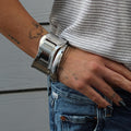 Silver Mini High Tide Cuff bracelet on a tattooed arm, worn with jeans and a striped shirt.