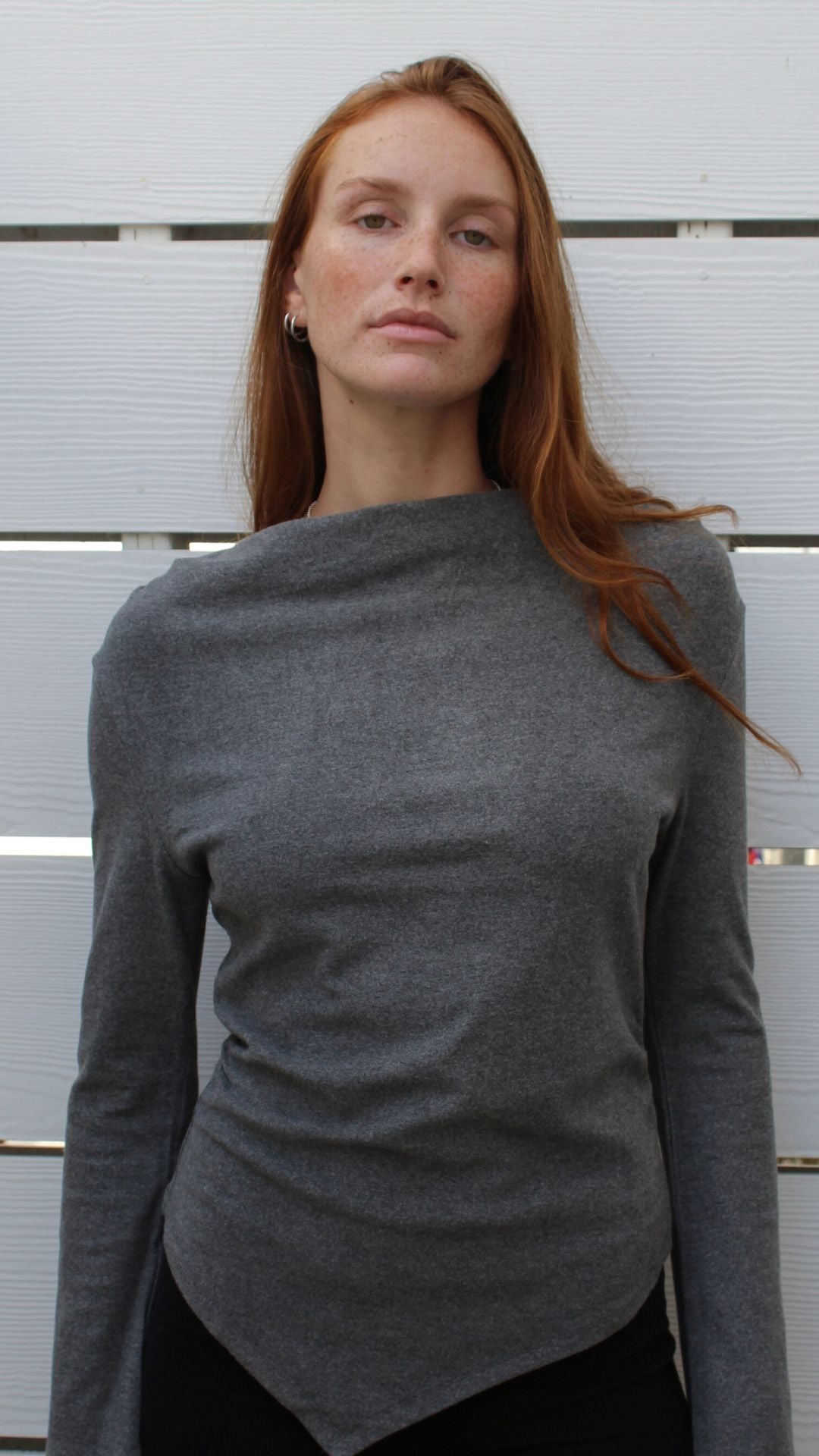 Woman in charcoal rayon-spandex Montauk long-sleeve top with an asymmetrical hem.