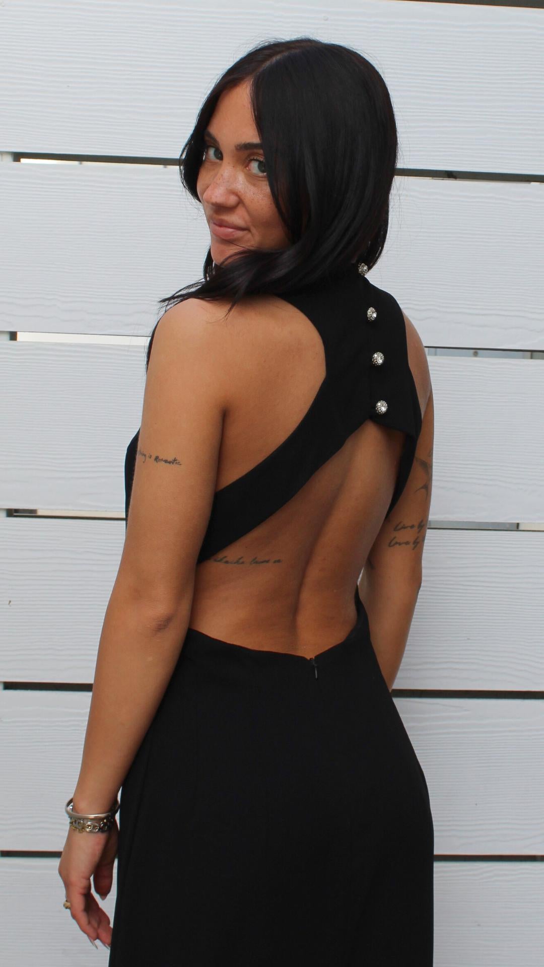 Black Rampage dress with open-back cutout and decorative buttons, modeled by a woman.