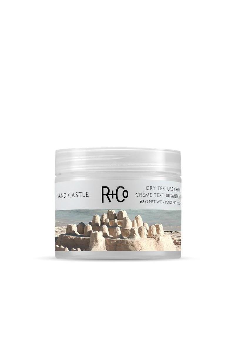 R+Co Sand Castle Dry Texture Creme in a clear jar with a sandcastle and ocean label.