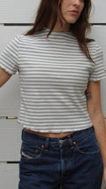 Model wears a striped ribbed short sleeve linen-rayon top with a mock neck and raw hem.