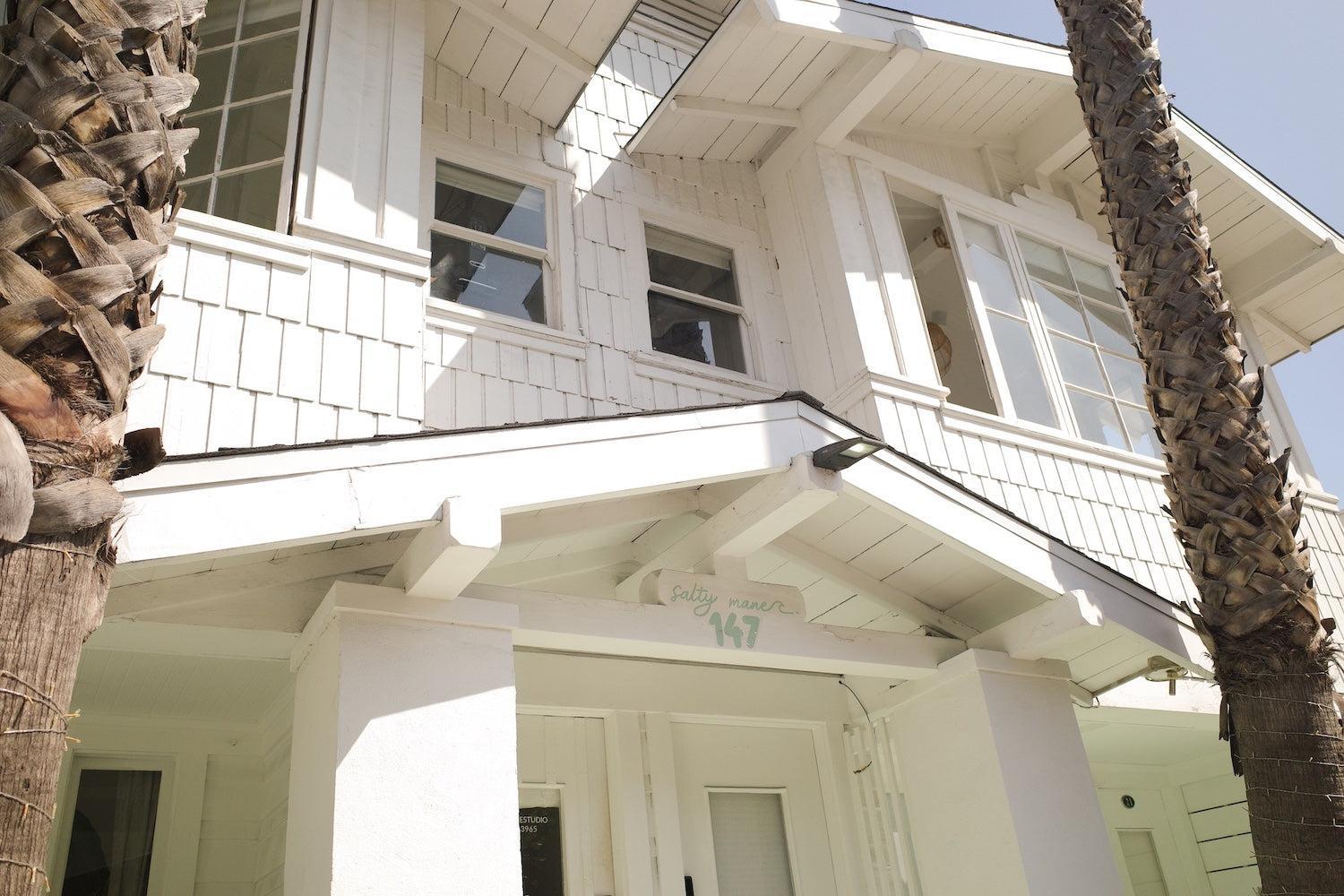 Experience the charm of Salty Mane Hair Salon, a bright white building with inviting windows and palm trees.