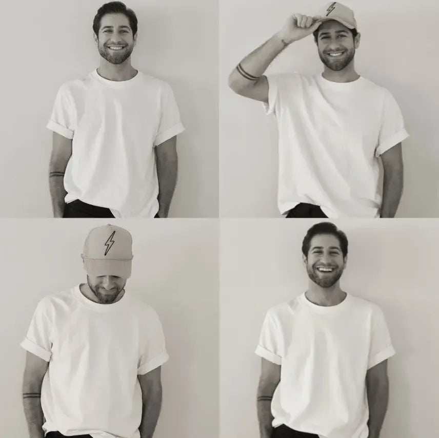 Daniel Bailey, a Salty Mane stylist, smiles in a white tee, showcasing his versatile style with and without a lightning bolt cap.