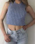 Model wearing a light blue ribbed sleeveless crop top with a high neck and light wash jeans.