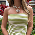 Chunky pearl necklace with a large, natural seashell pendant on a woman wearing a green and white striped top.
