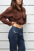 Model wearing a brown cropped cotton button-up shacket with chest pockets and dark wash jeans.