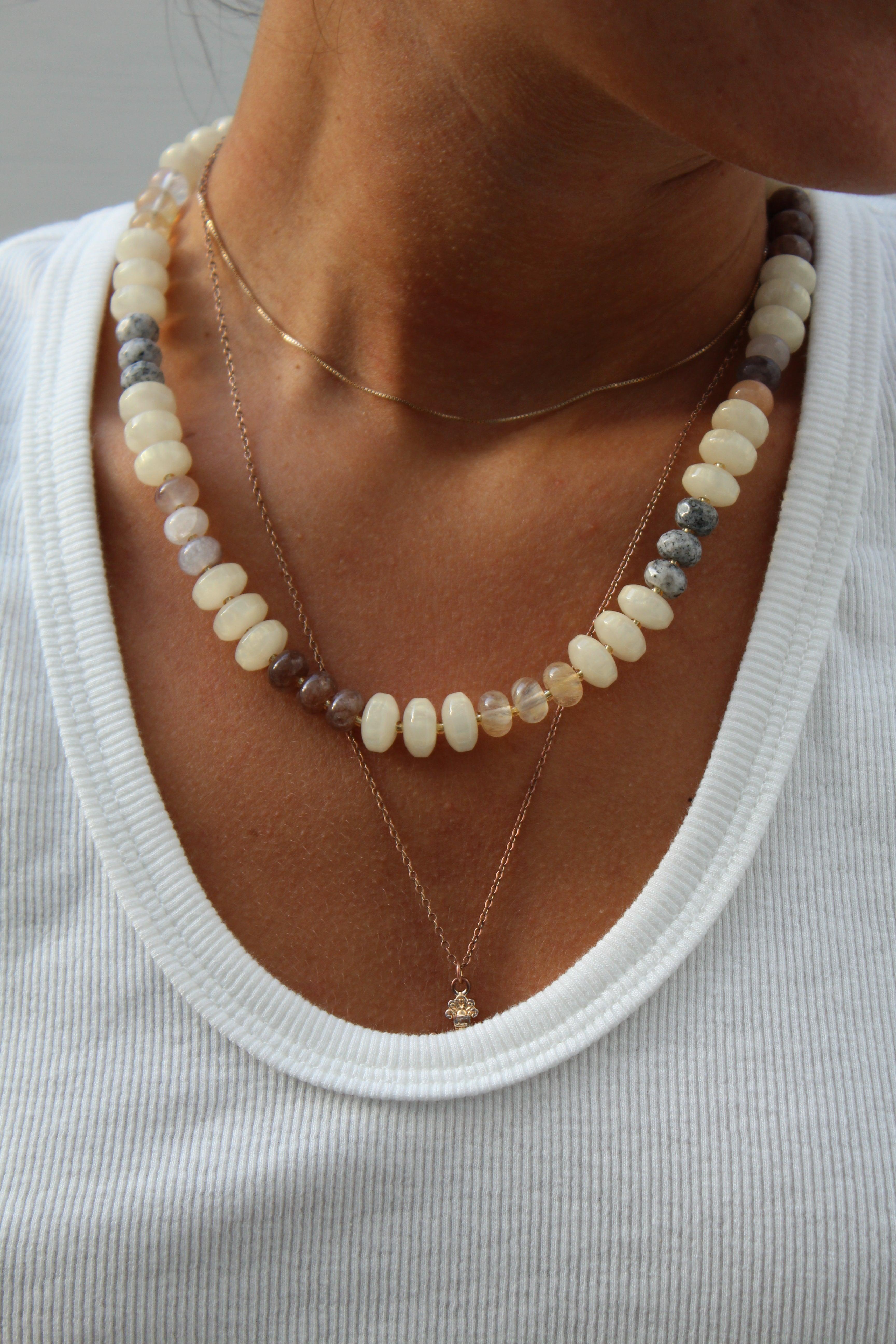 Sunstone multi-nugget beaded necklace with varied cream, grey, and brown stones, layered with a delicate gold chain.