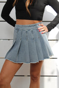 Light wash denim pleated mini skirt with a raw hem, worn by a model.