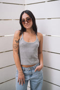 Woman in a grey ribbed scoop neck tank top, light wash jeans, and sunglasses.