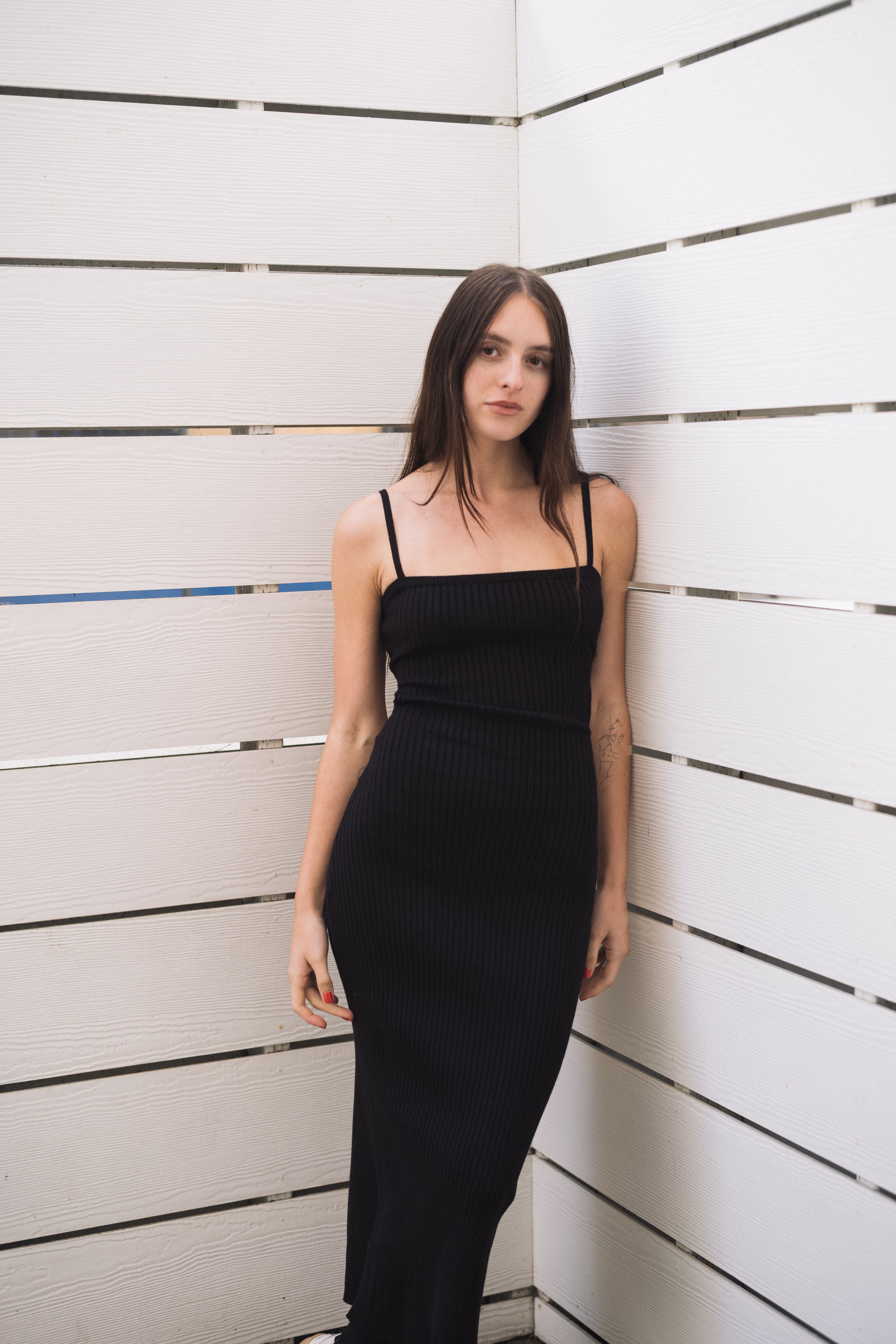 Model in a black ribbed open-back midi dress with spaghetti straps, size S.